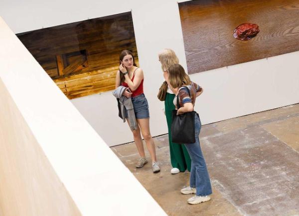 Three girls stood looking at artwork in a blank exhibition room
