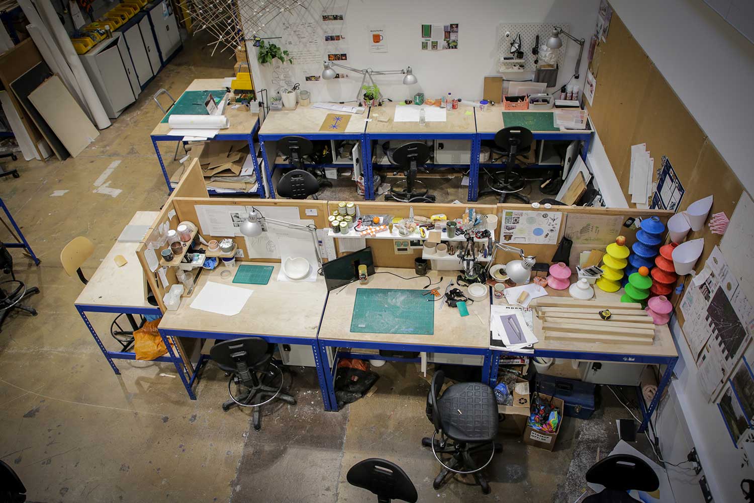 A series of desks pushed together, with each students' work laid out on top