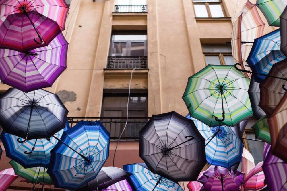 Multicolored umbrellas arranged around the front of a building