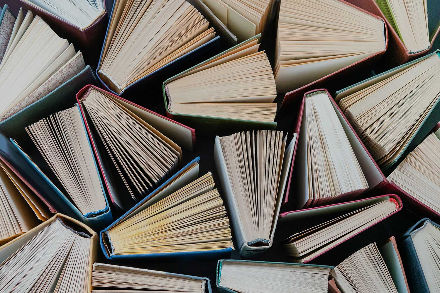 A number of books laid partially open on a table