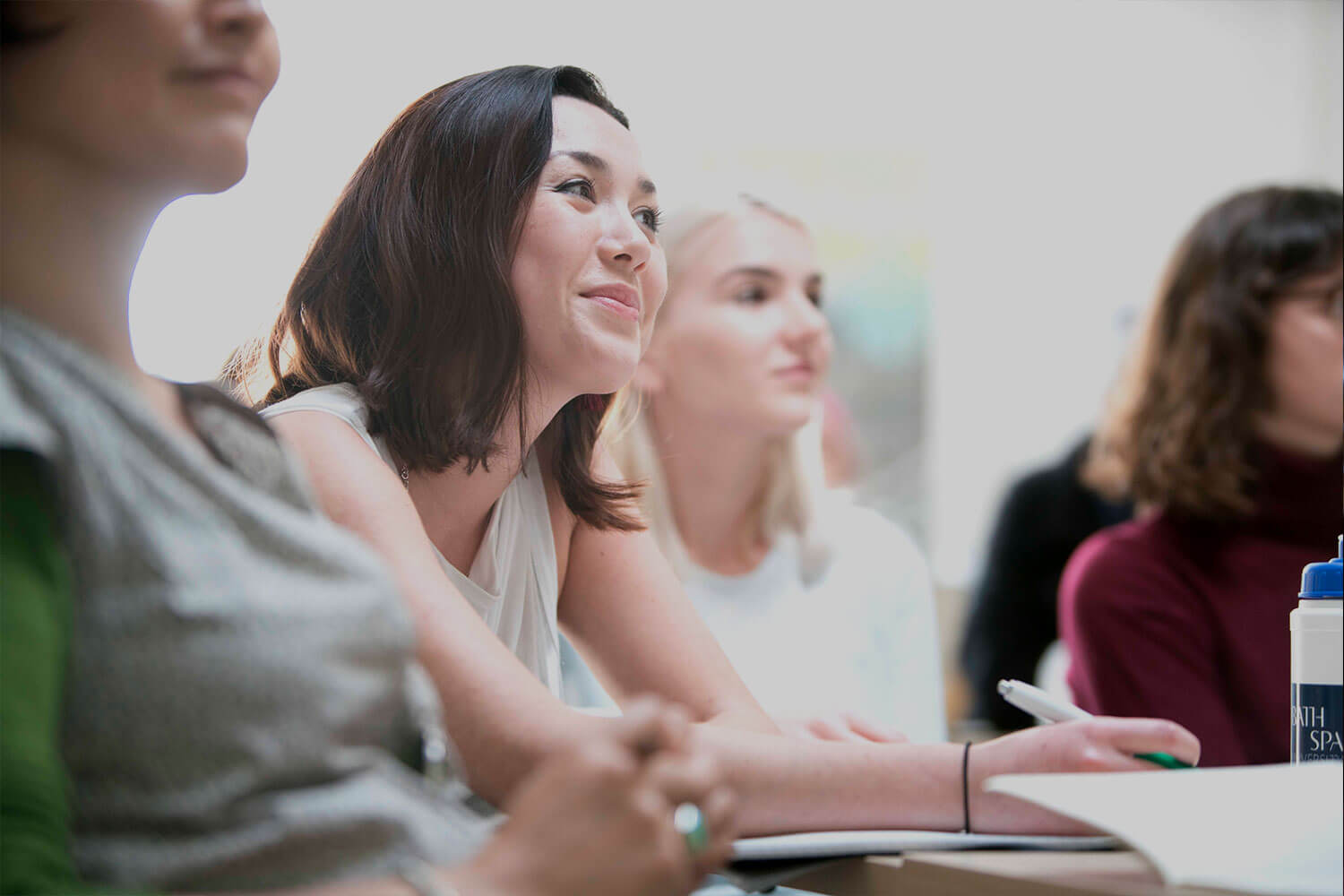 Woman smiling and taking notes in a seminar class