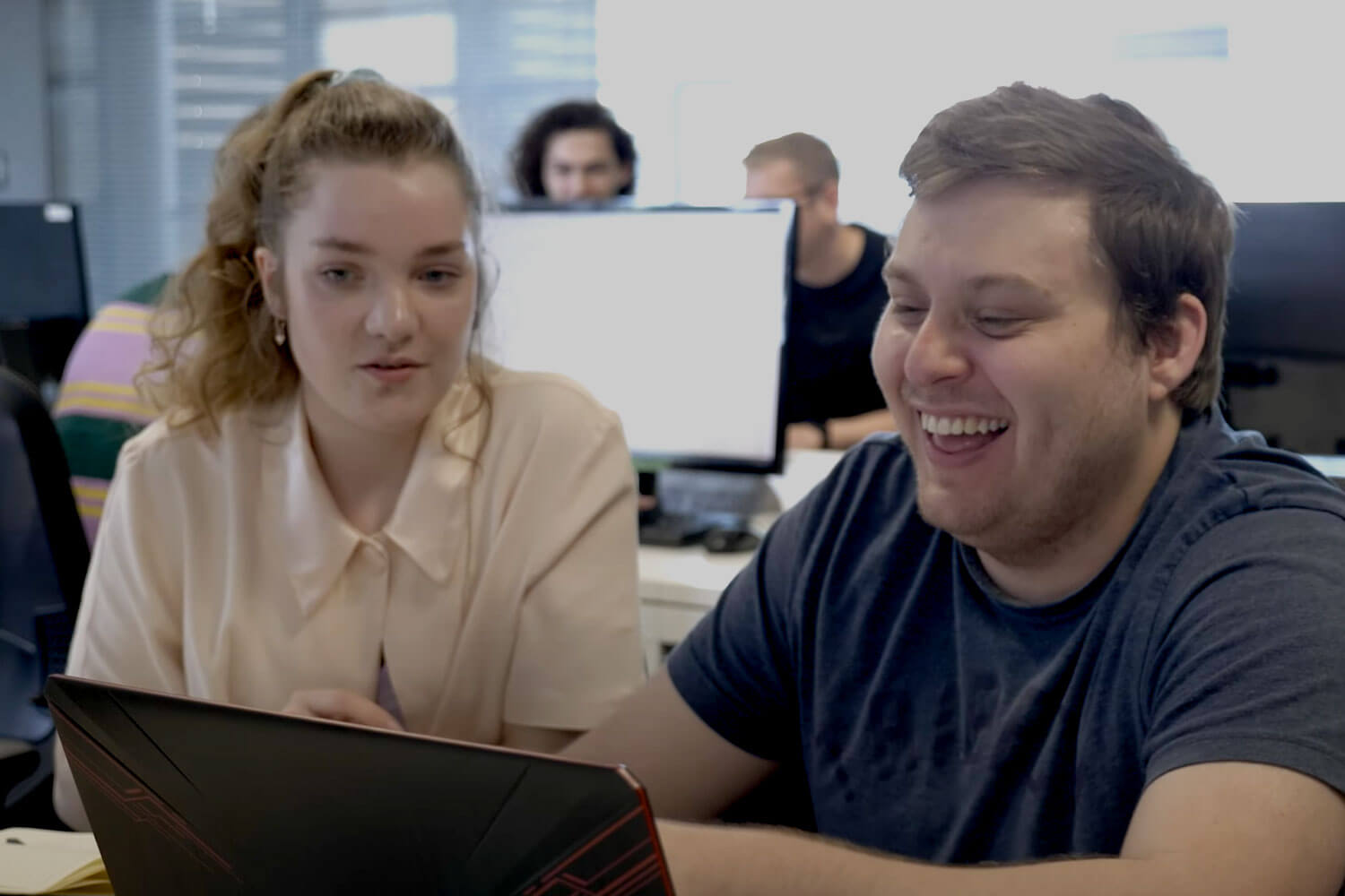 Two students share a computer screen in a Mac lab