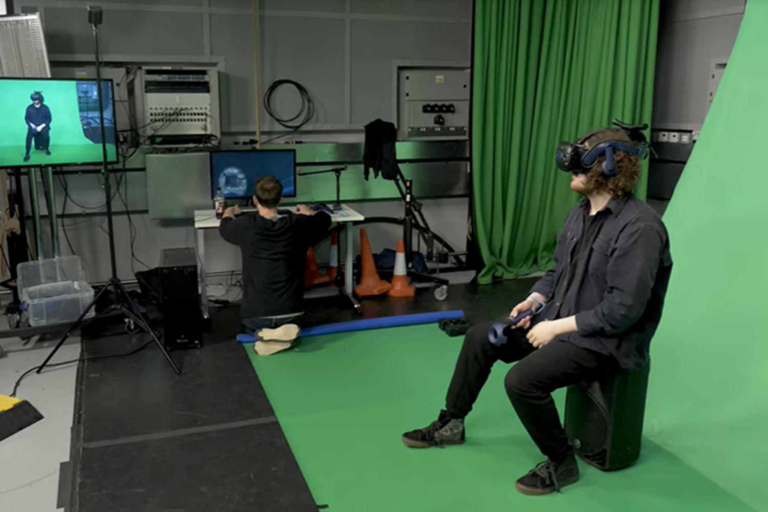 A person wearing a VR headset and sitting in front of a green screen
