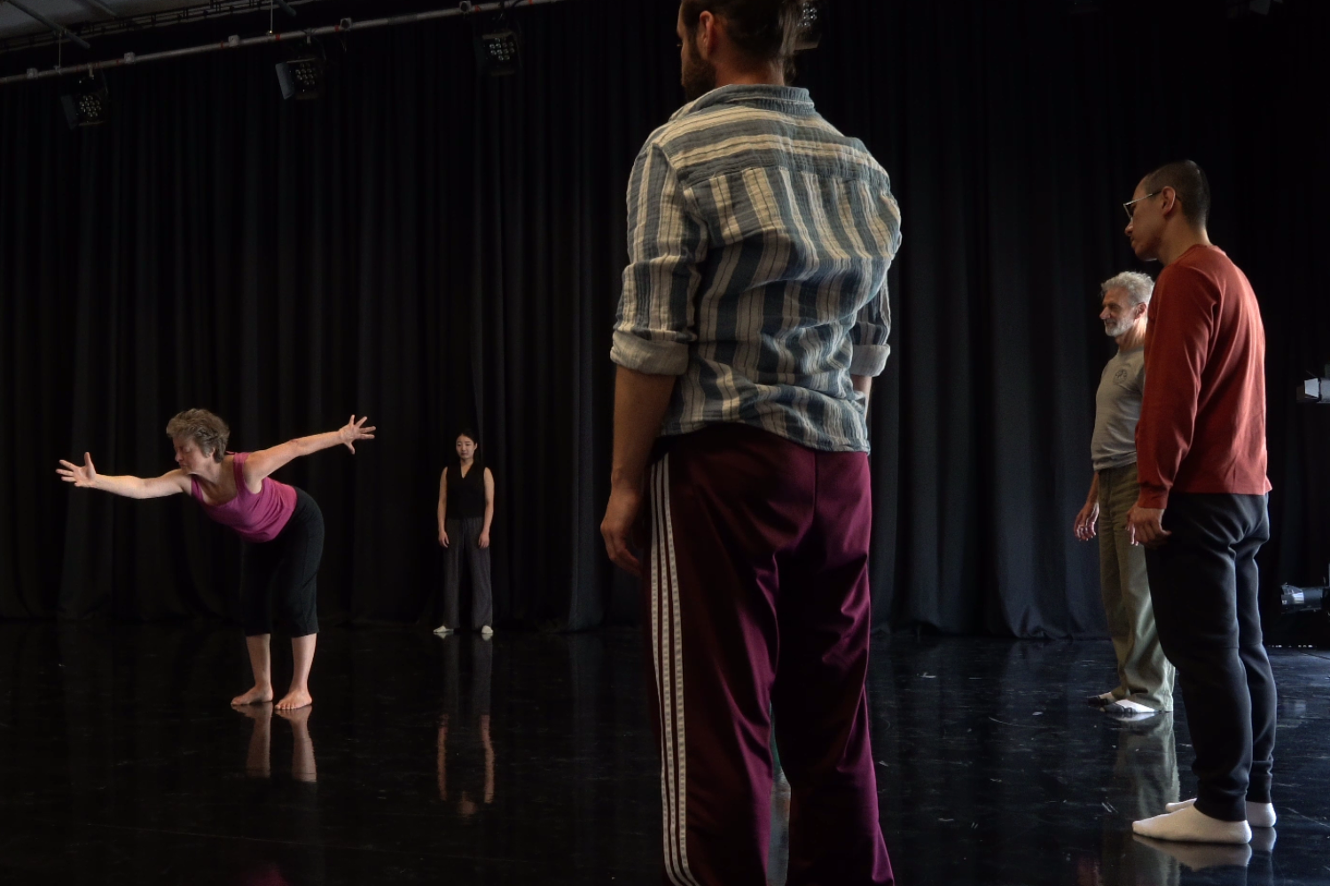 A group of dancers watch as one person performs in the middle of the floor