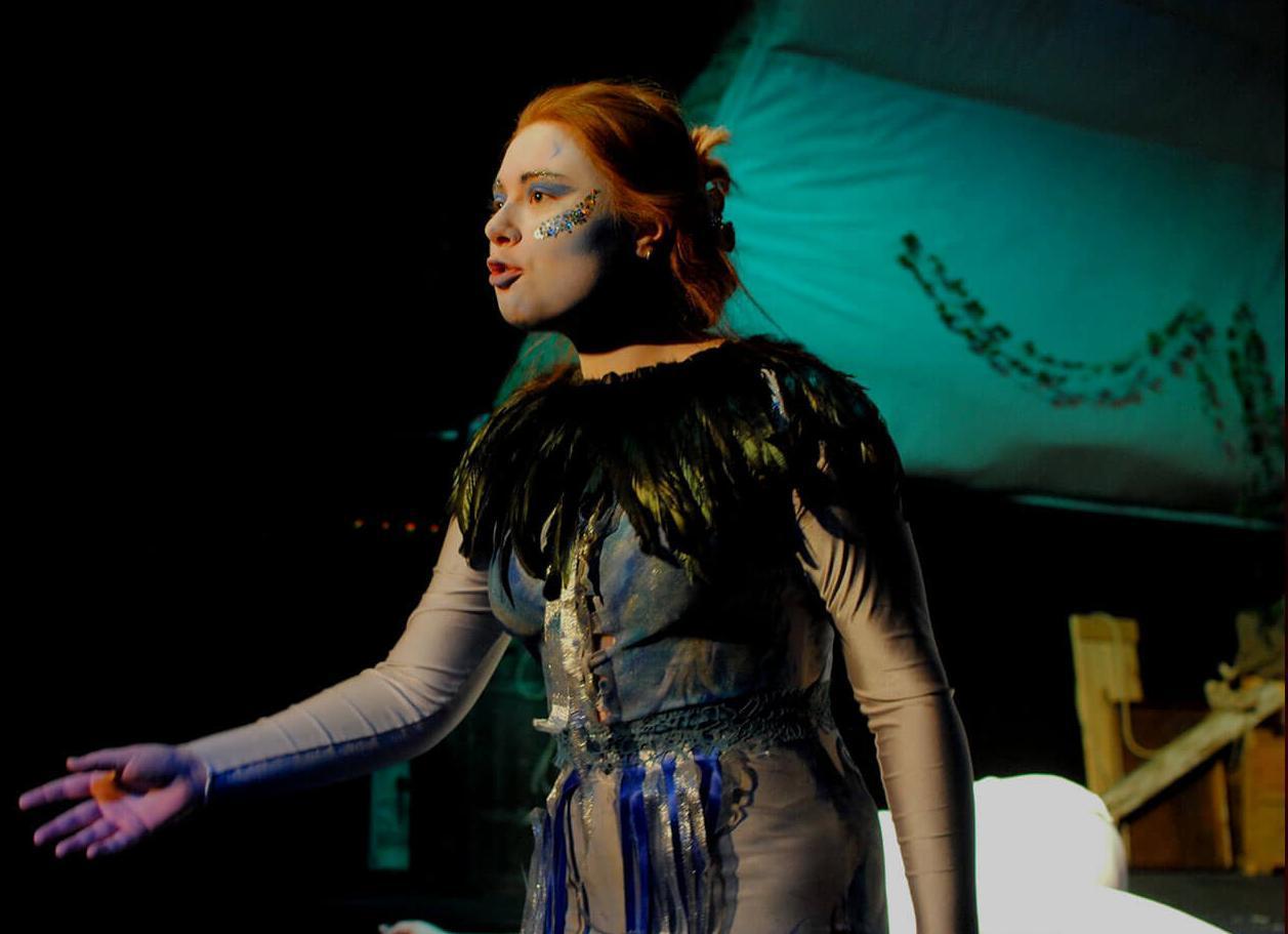 Student on stage performing in a feathered costume