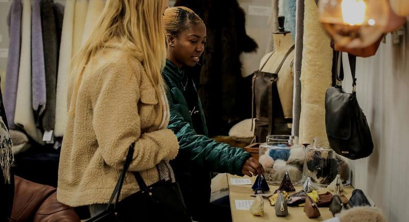 Two students examining purses in a leathercraft studio