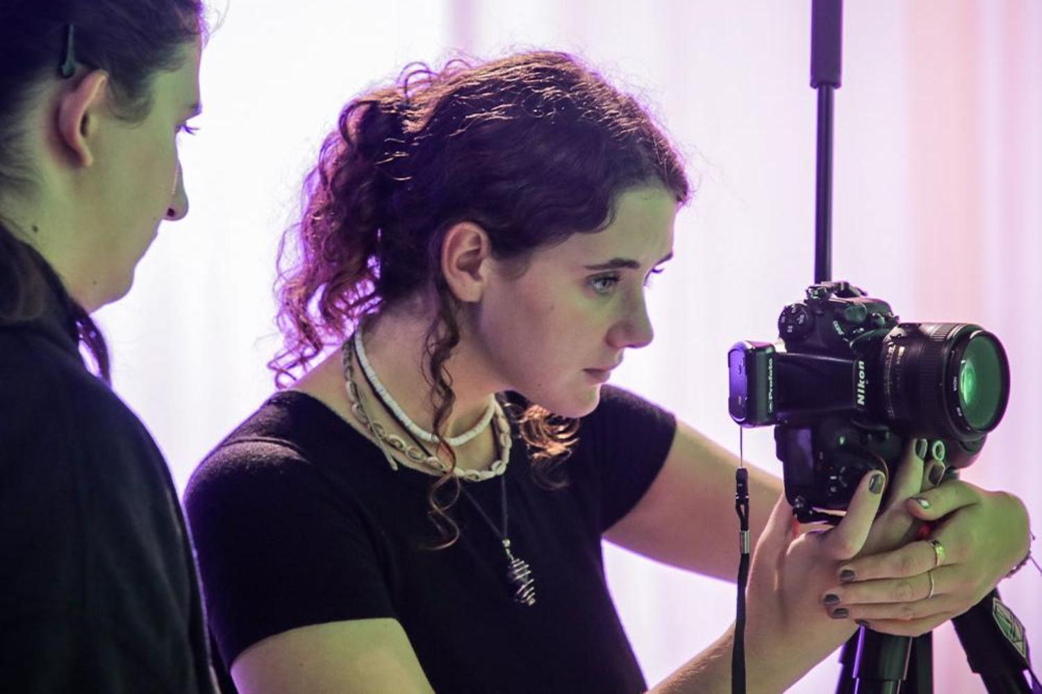 Two young people looking through TV camera in a studio