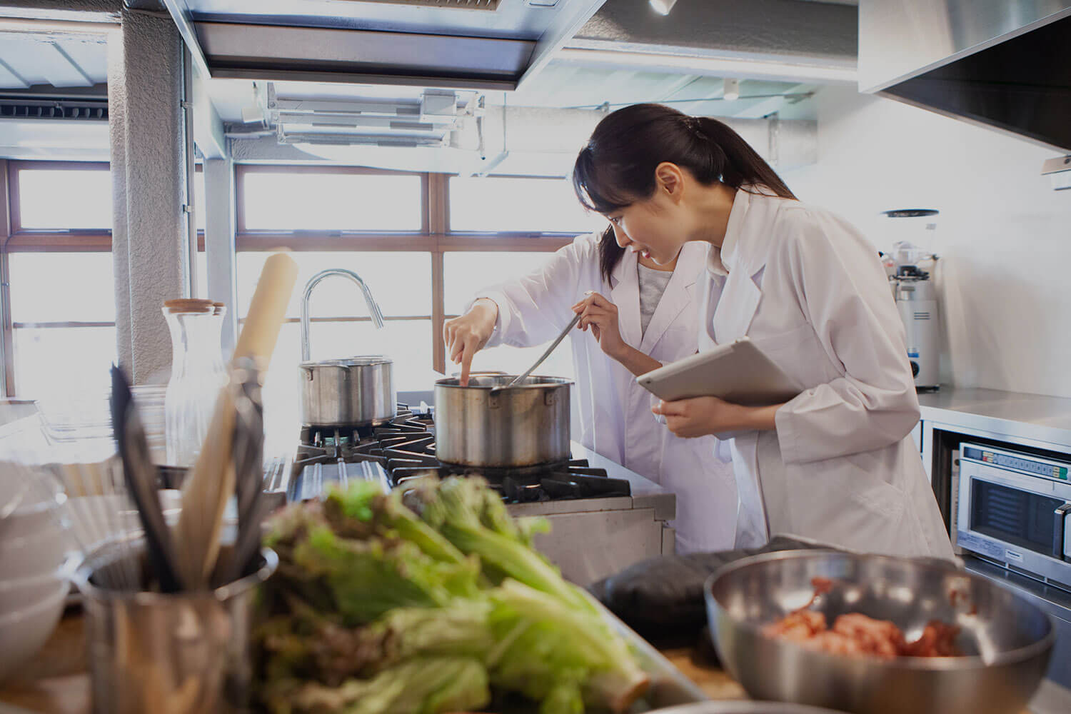 Two female students stand over a stove