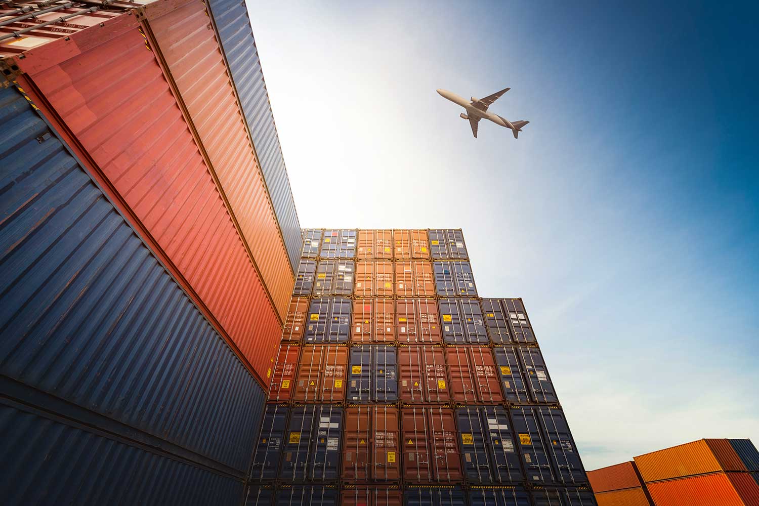 An abstract photo of a plane flying over shipping containers