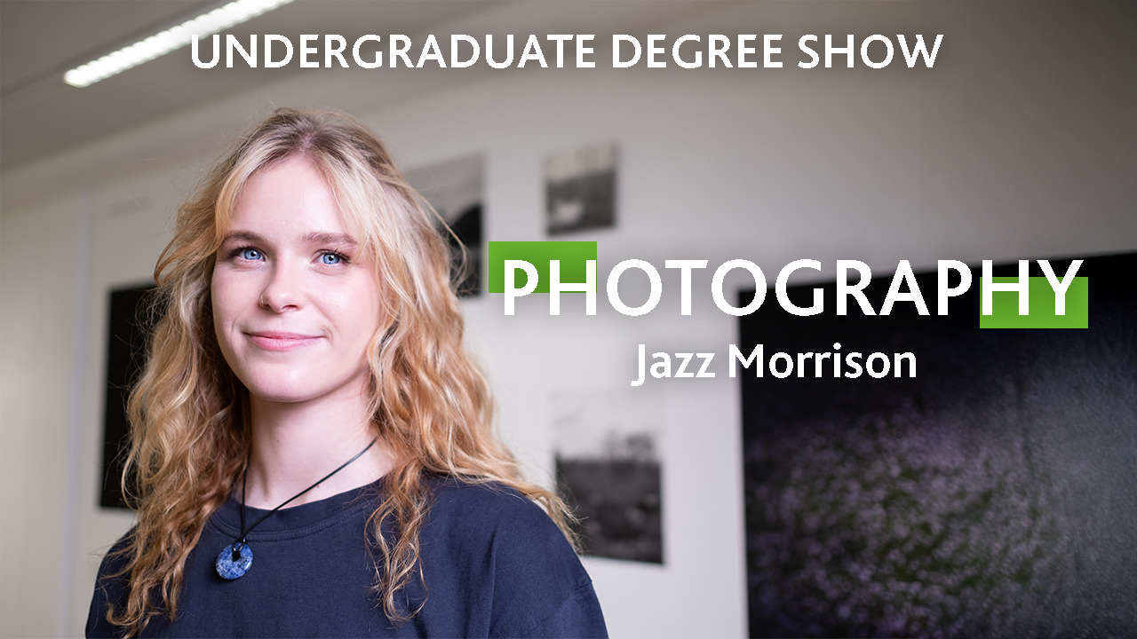 A person with long blonde curly hair and blue eyes smiles at the camera