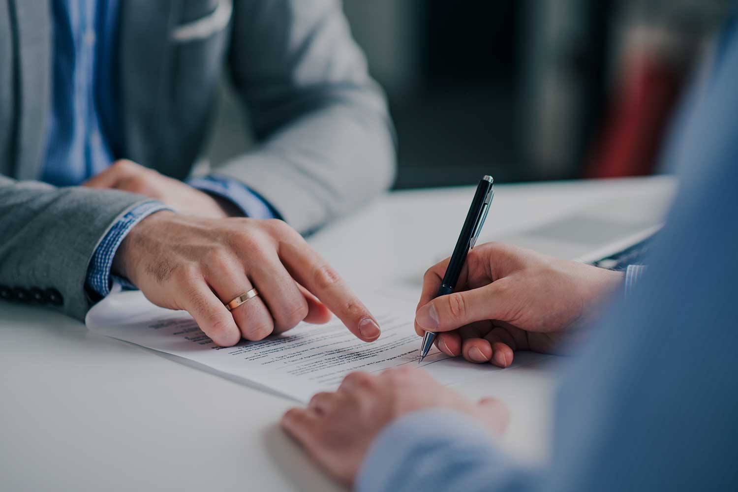 A solicitor oversees a client signing a contract