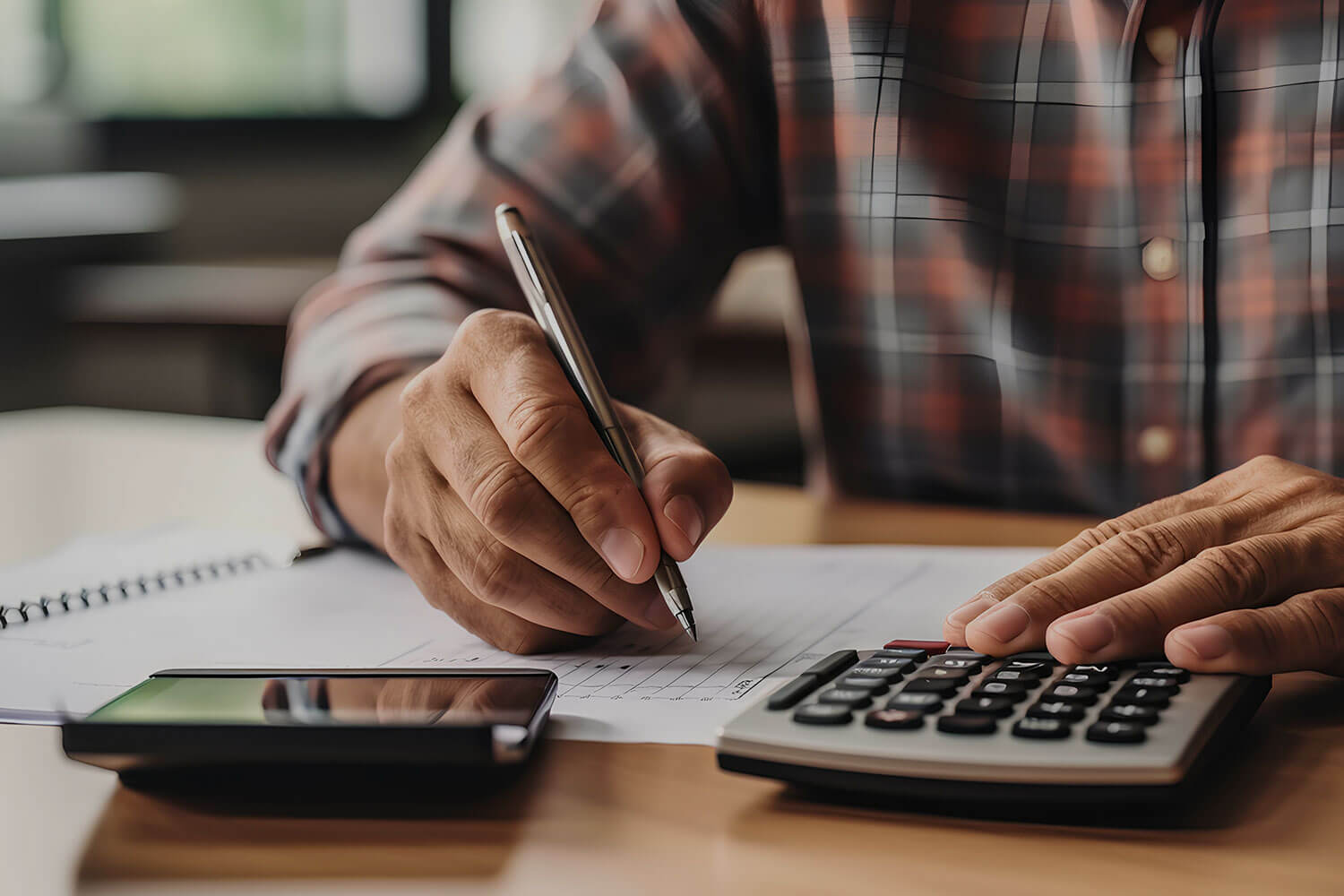 A man uses a calculator and writes notes