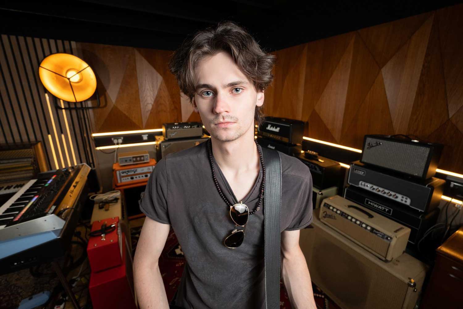 A student stands in a dimly lit recording studio