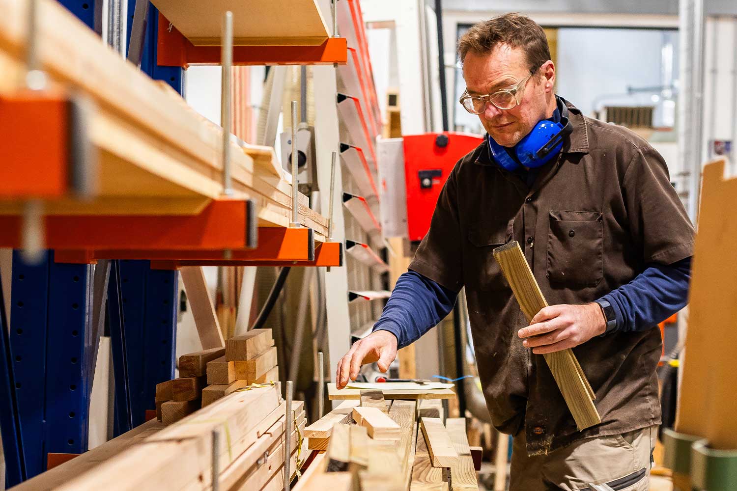 A person rearranges pieces of wood in the workshop