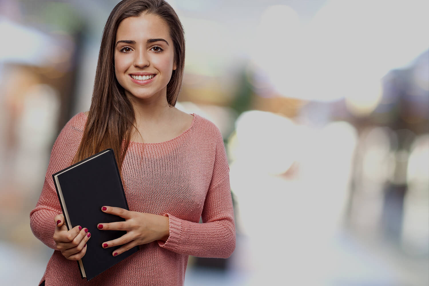 young woman smiling and holding a book