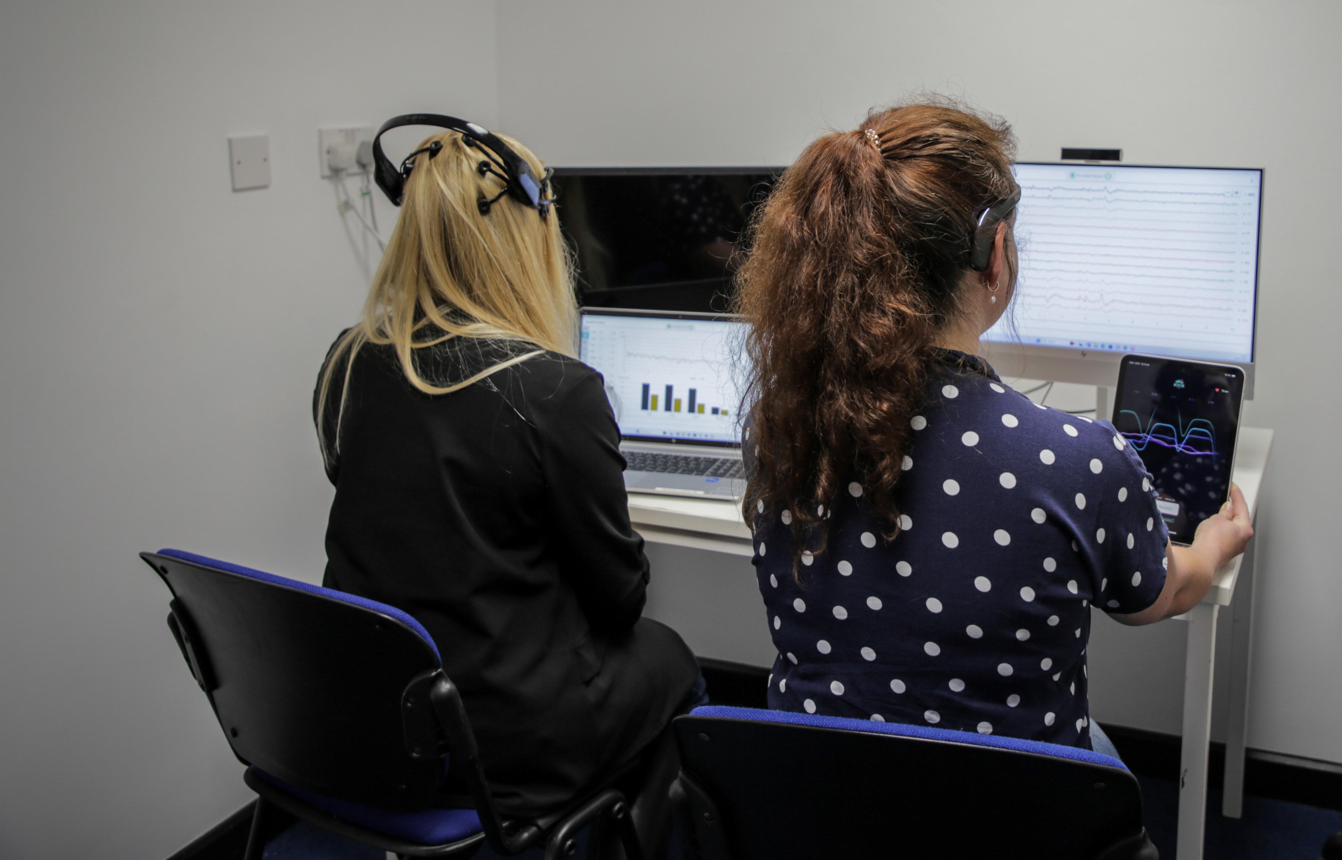 Two students sit at computers and process cognitive data