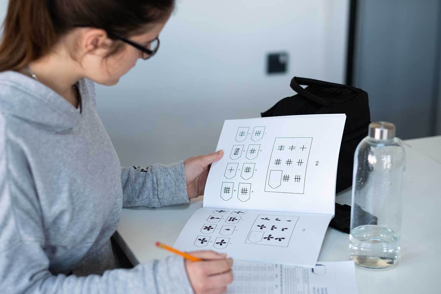 A student leans over a desk and completes a workbook