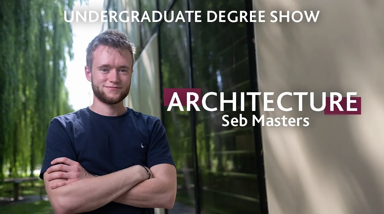 A person stands with their arms crossed in front a building surrounded by willow trees