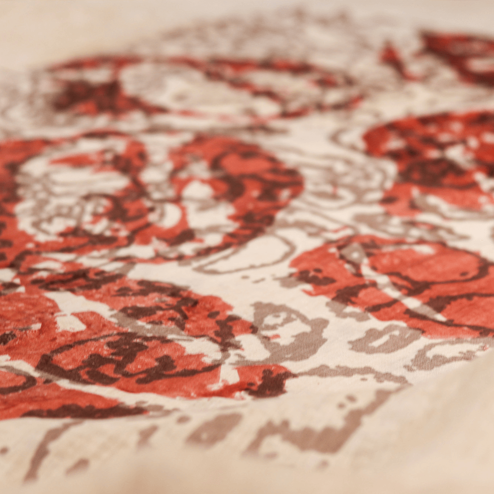 A photo of a piece of fabric with red and brown designs printed on top in ink.