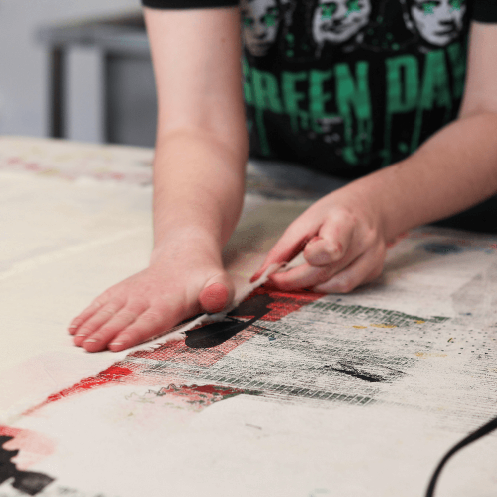 A student placing one piece of fabric on top of another to transfer black and red ink