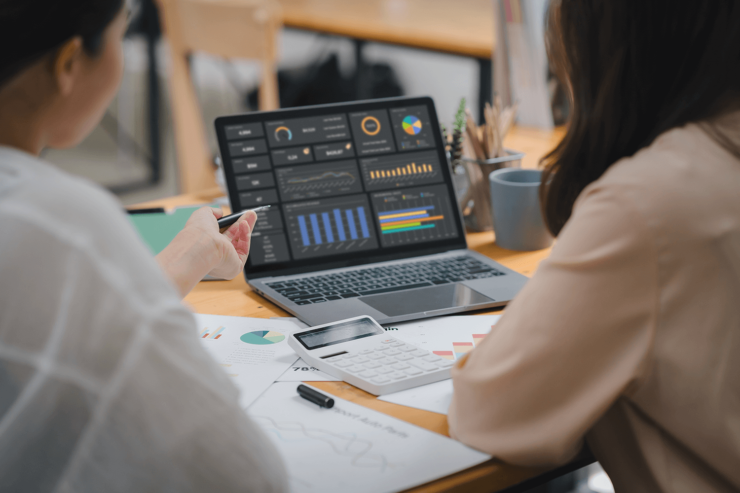 Two coworkers sat at a desk looking at a data dashboard