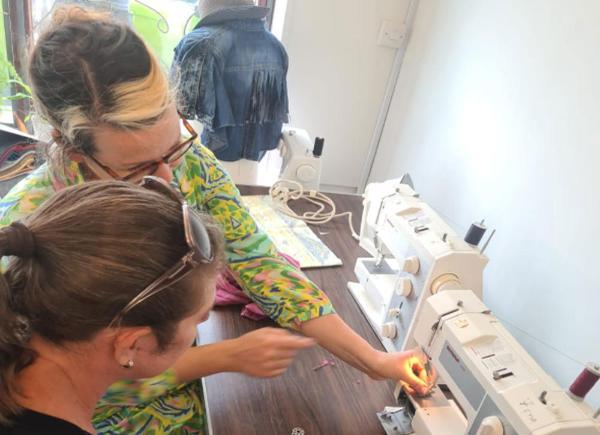 Image of two women sitting over a sewing machine