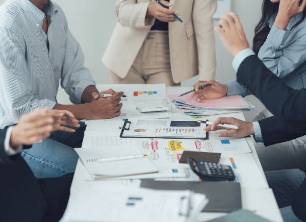 A group of coworkers sit around a table discussing strategies