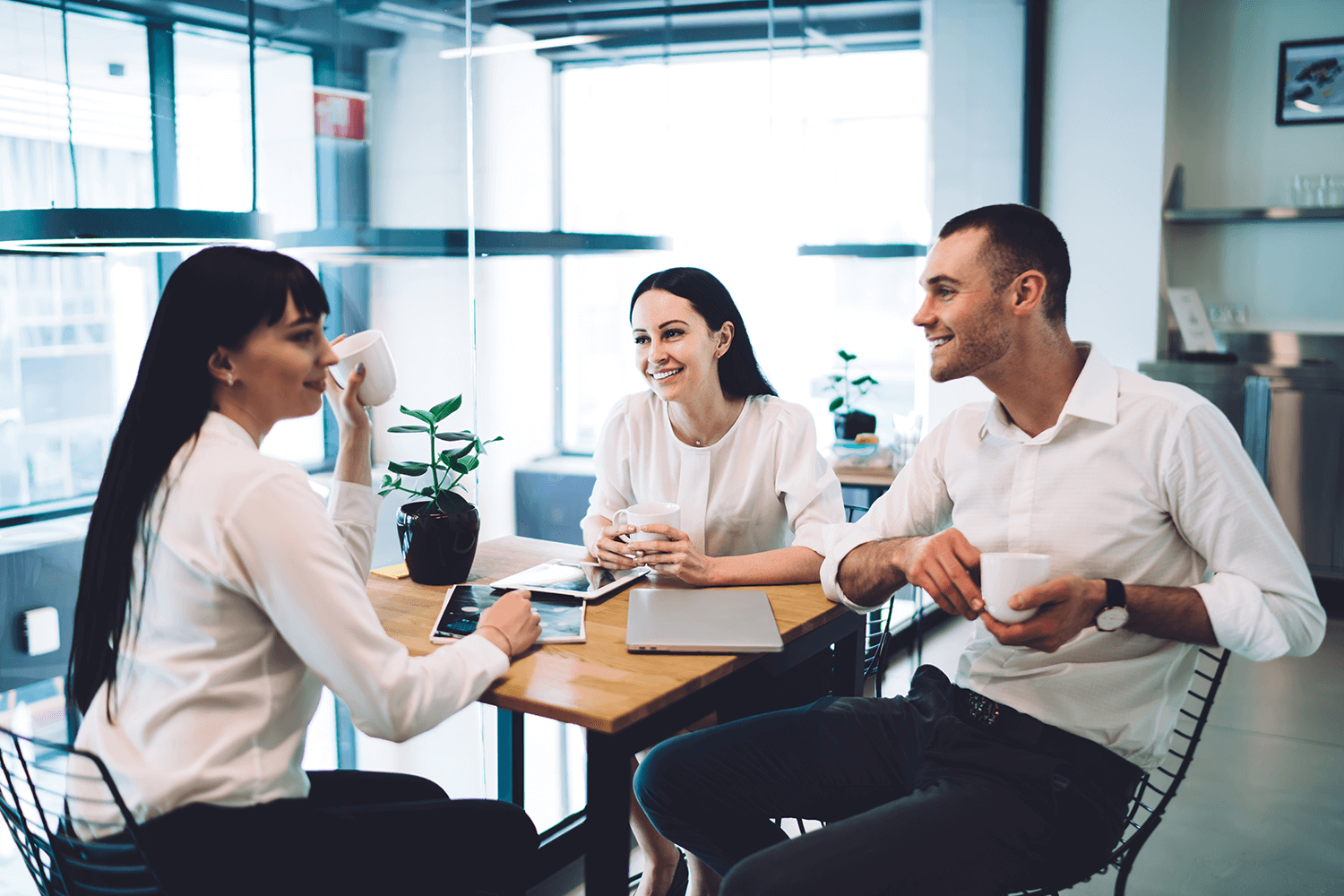 Three coworkers sat around a table talking