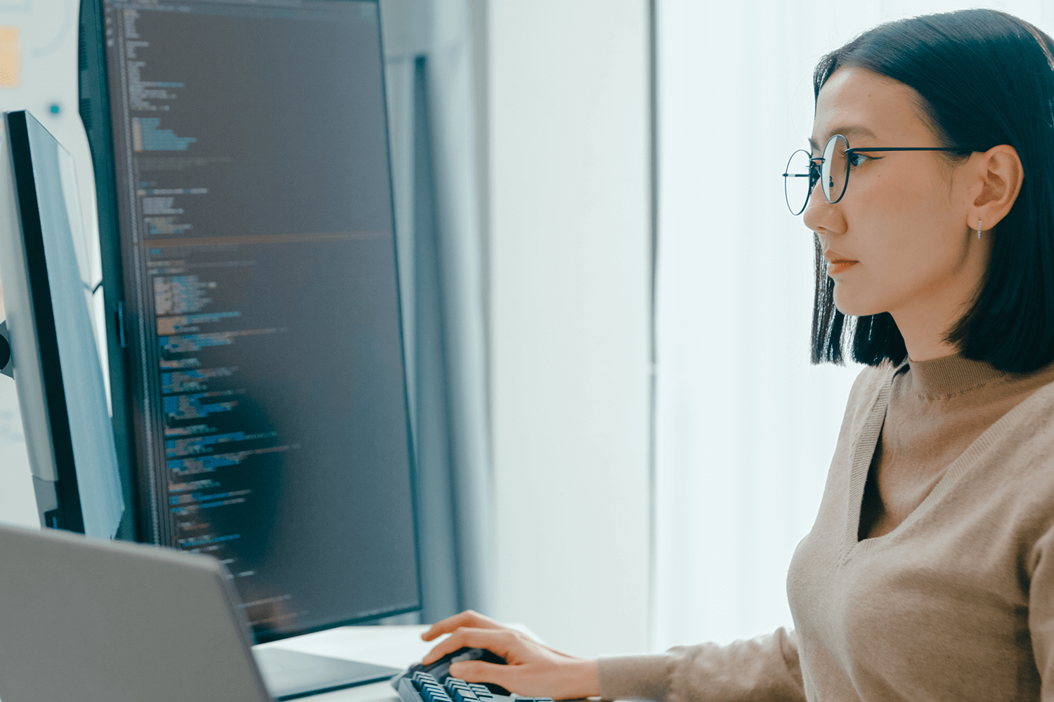A woman sits at her desk looking at code