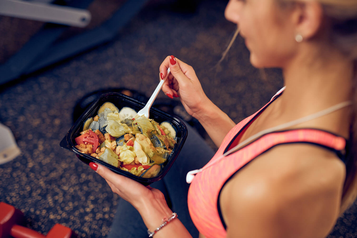 Top view of woman eating healthy food while sitting in a gym