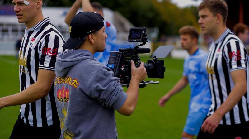 Student filming players on a pitch