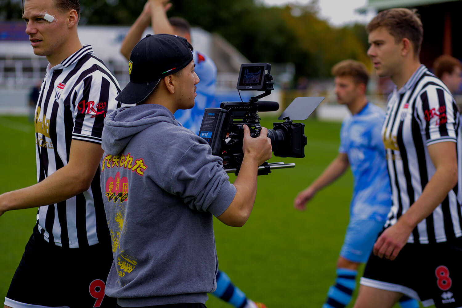 Student filming players on a pitch