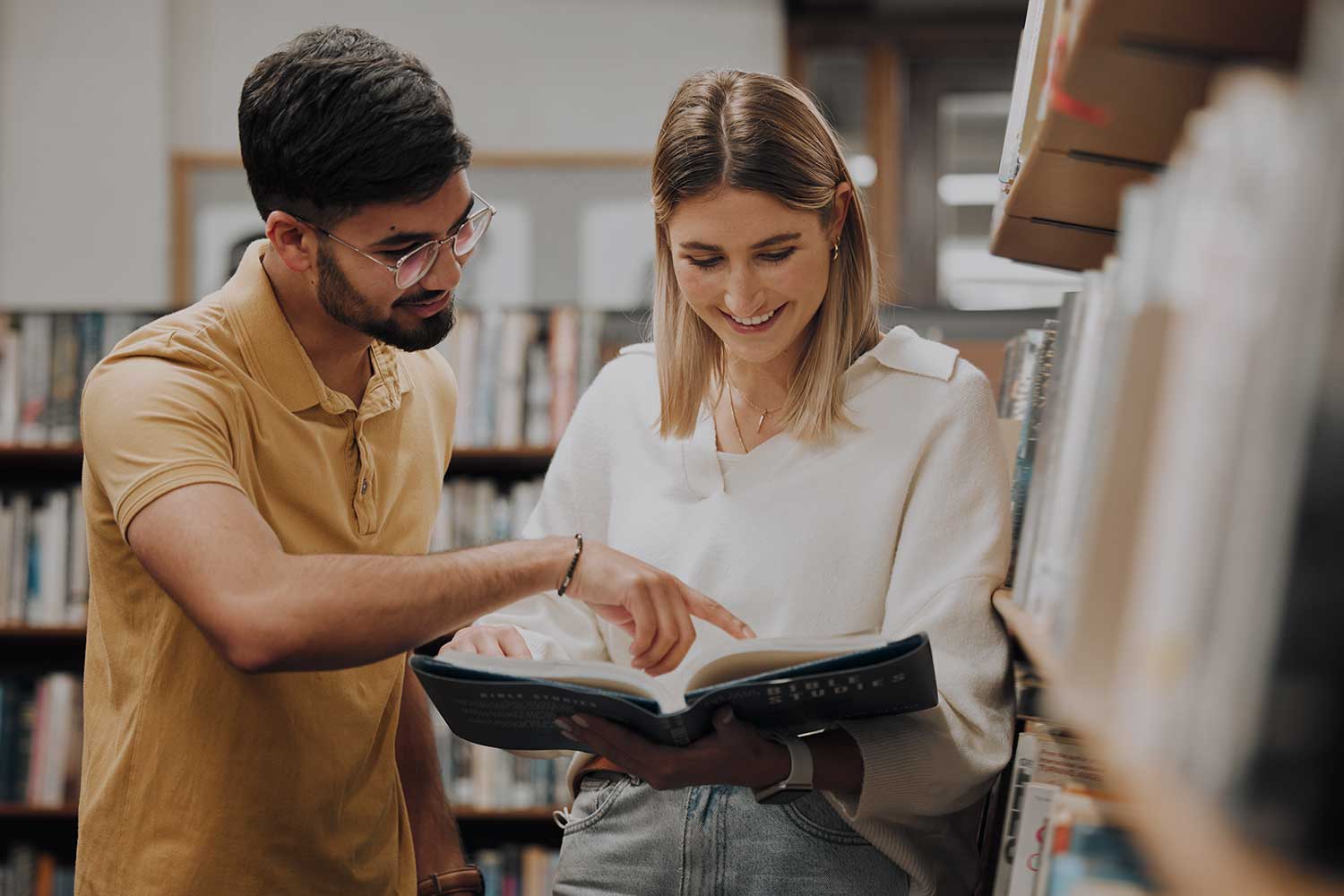 Two students look through a library book