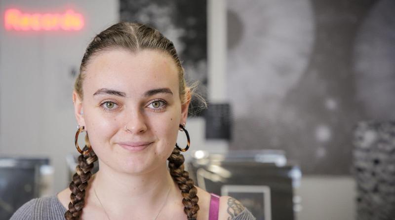 Student looks confidently at the camera with their monochromatic exhibition behind them