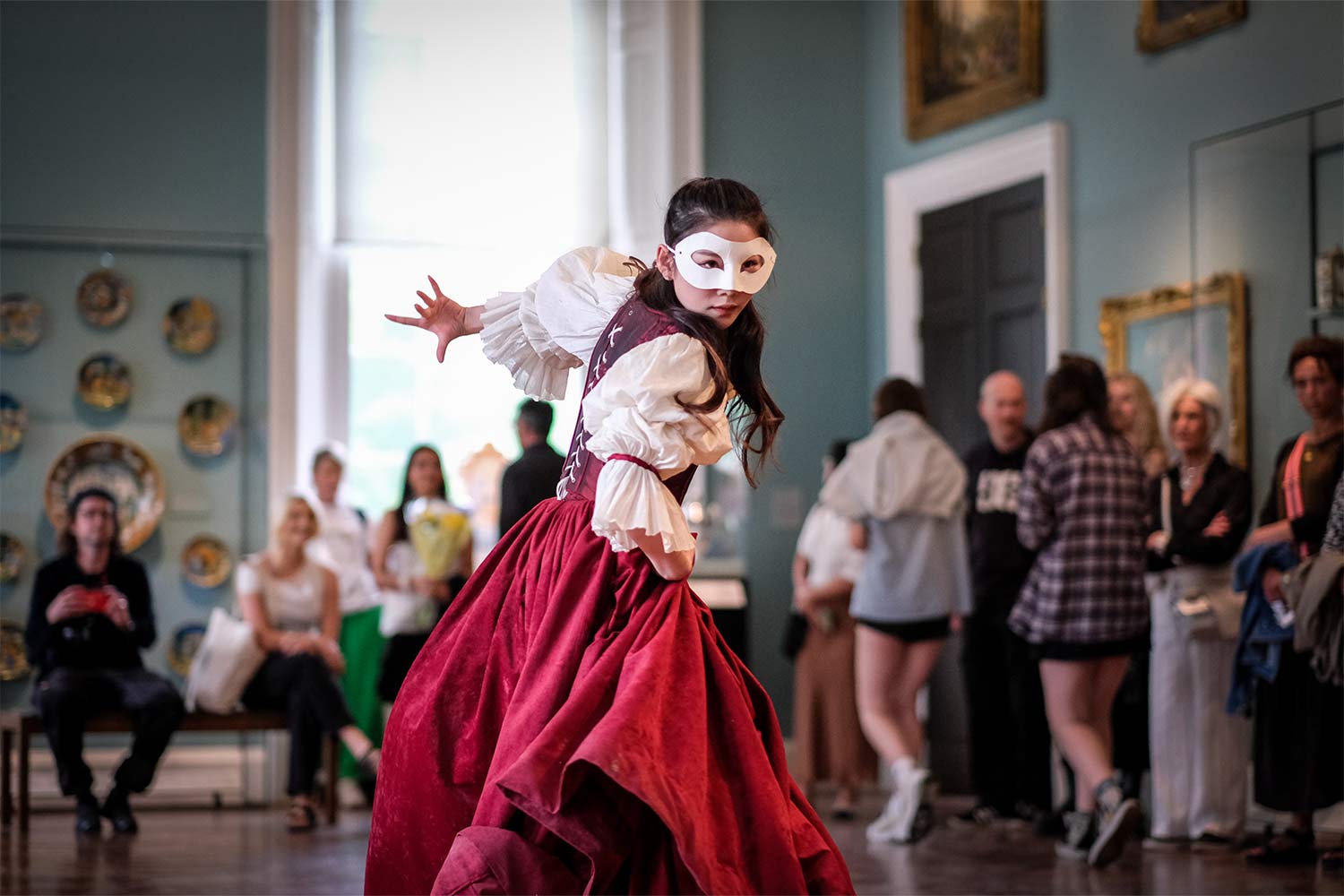 Person in traditional dress and mask acting in theatre setting