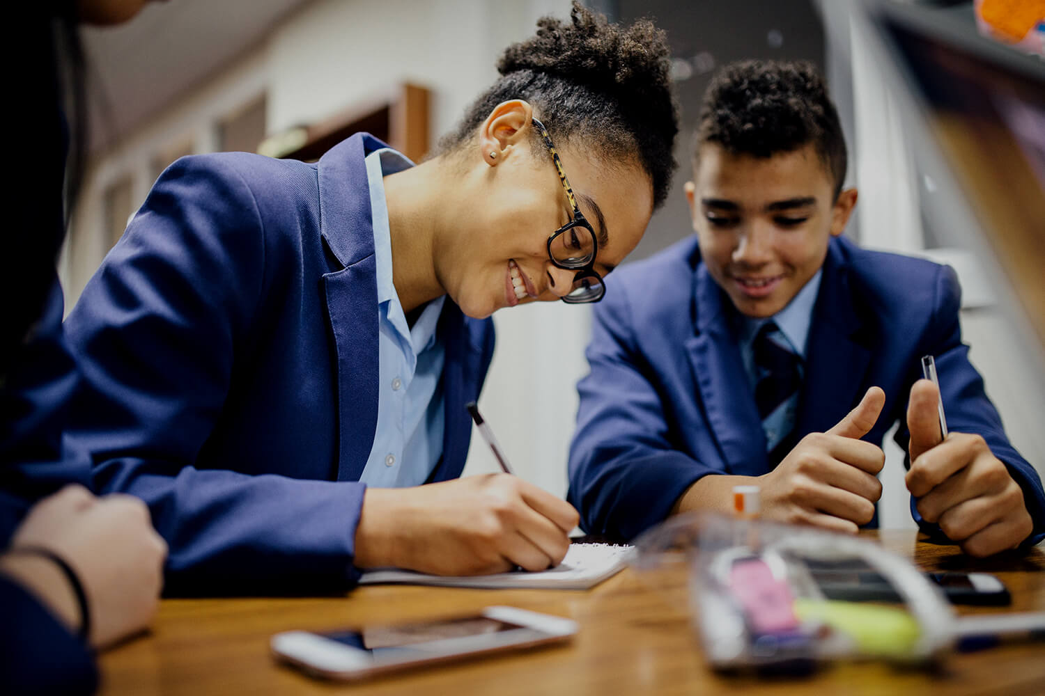 Two high school students writing notes.