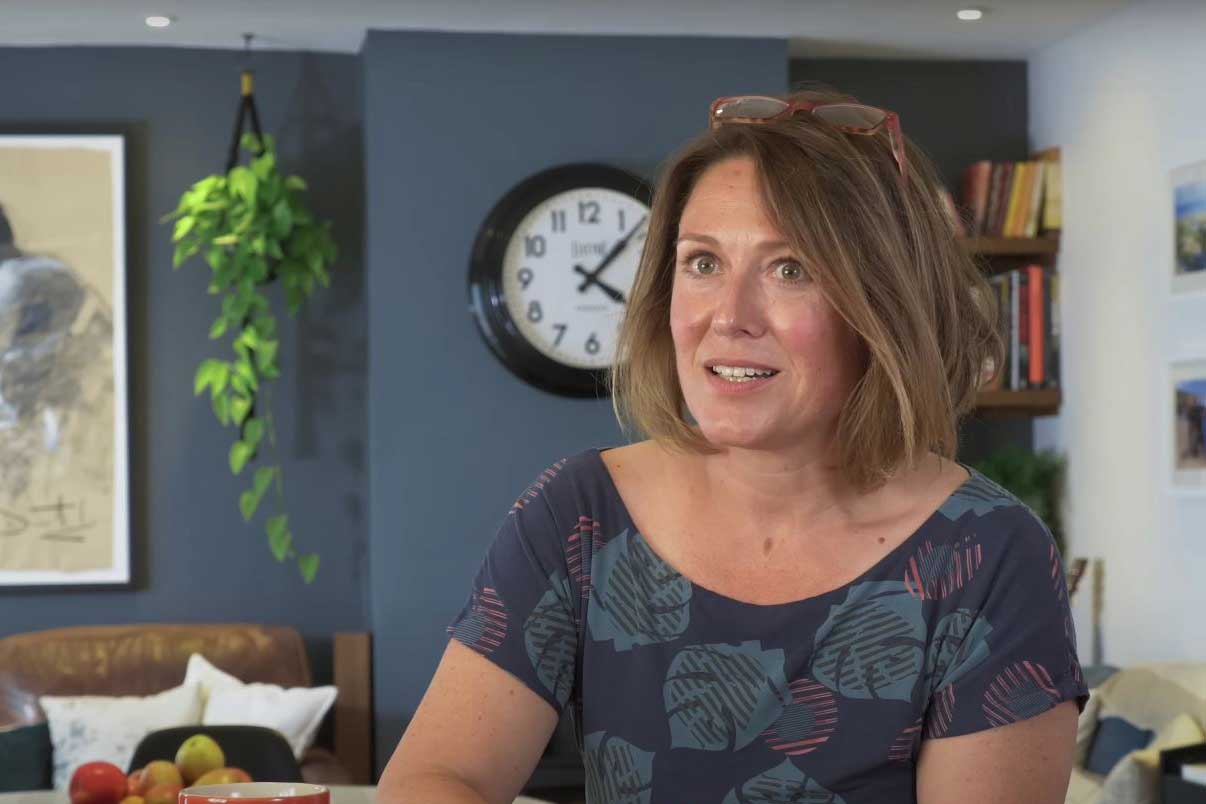 A woman with a short brown bob talks to the camera