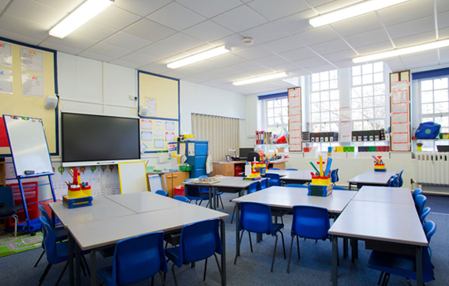 White desks and blue seats in a colour-filled empty classroom