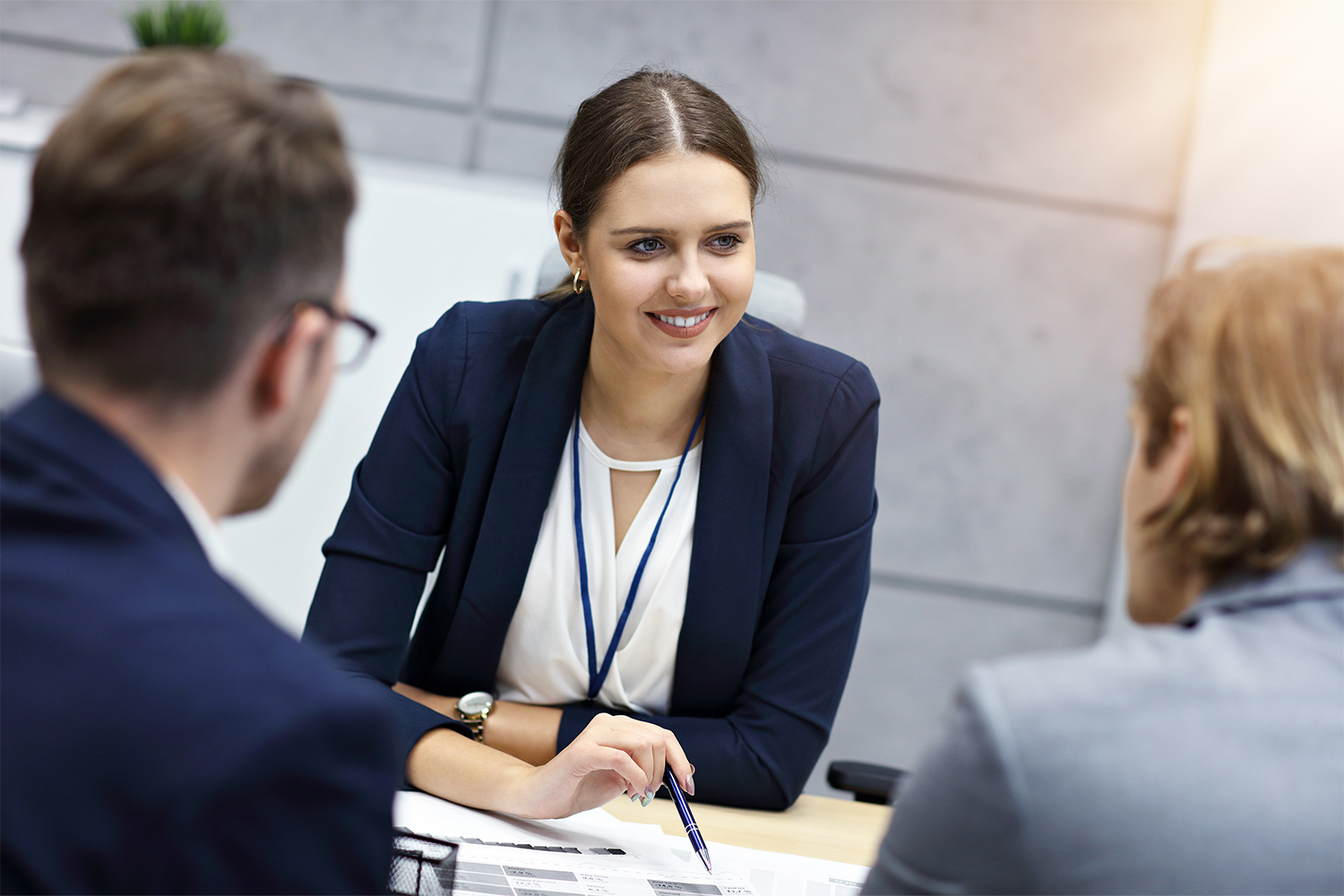 Young person in suit jacket leaning into conversation over desk