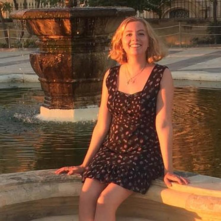 A person with short blonde hair smiles at the camera