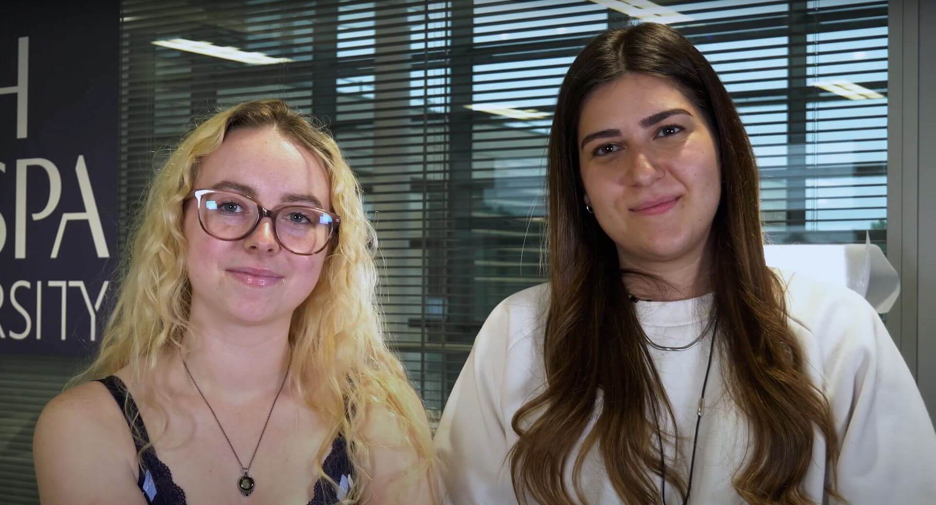 Two students being interviewed smile at the camera