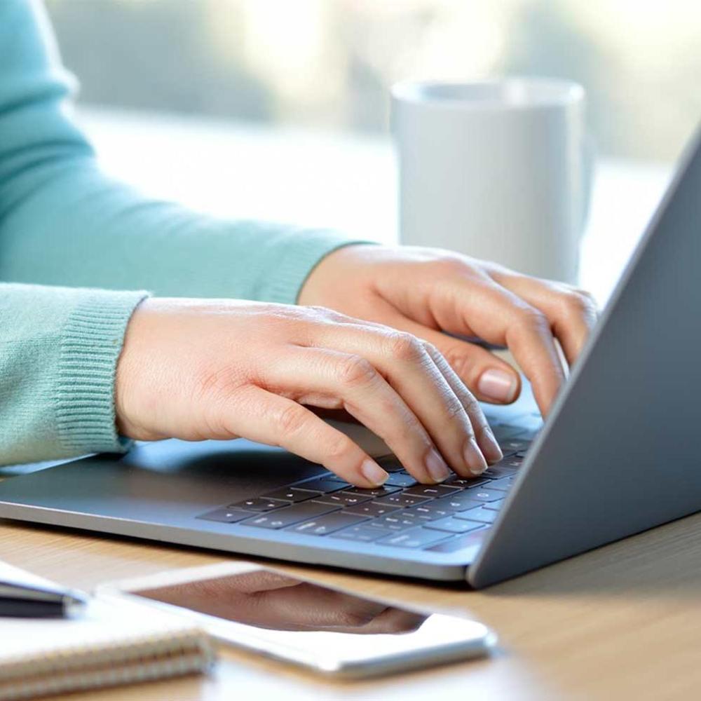 Person's hands on a light grey laptop