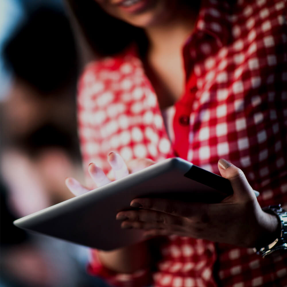 A person in a red and white checked shirt using a tablet