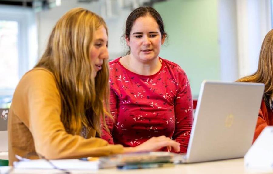 A student and teacher look at a laptop screen together