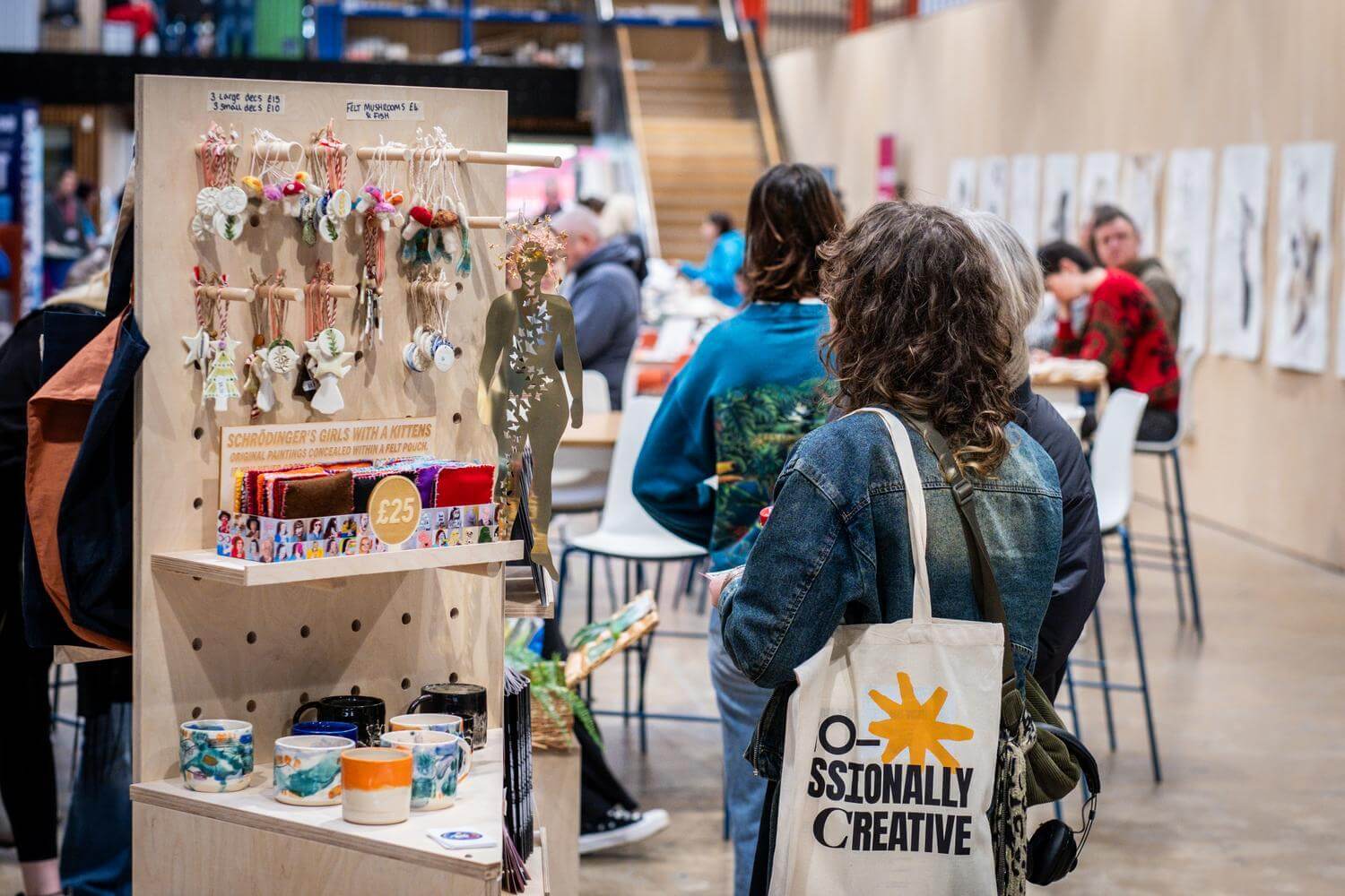 A stand selling small handmade items and people walking around a large open plan corridor