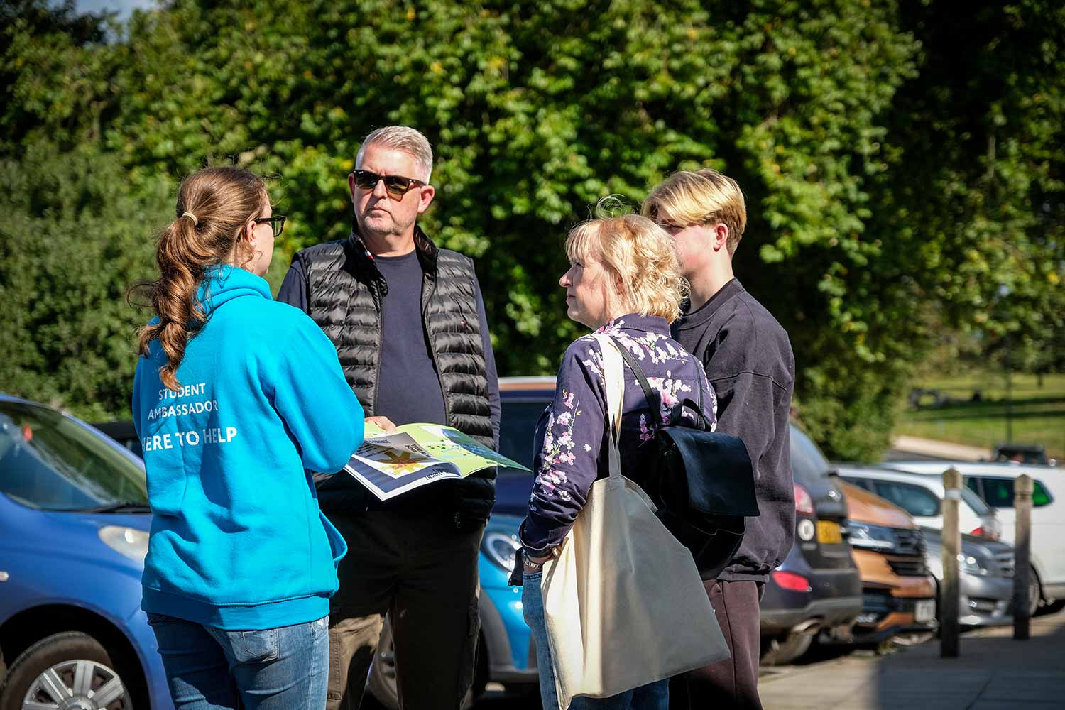 Student ambassador giving two adults and young person directions in car park
