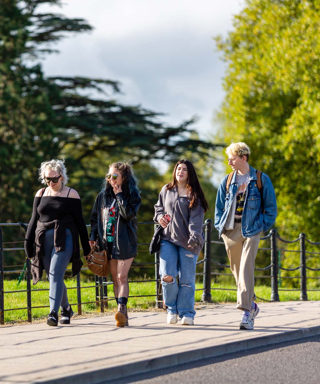 Group of four students walking along a path on campus.