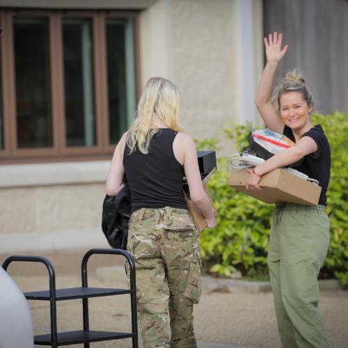 Two female students carrying cardboard boxes