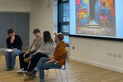 Four students sat in chairs having a discussion