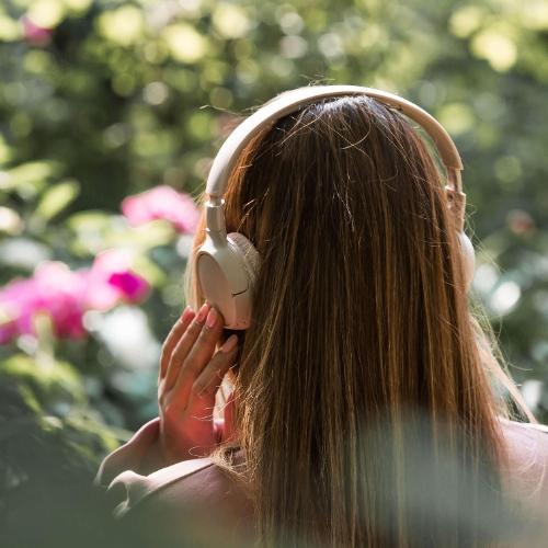 A woman walking amongst flowers listening to music in her headphones